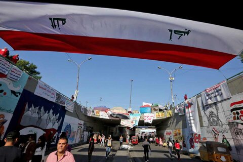 پرچم‌های عراق و نقاشی‌های دیواری اعتراضی روی دیواره‌های یک تونل در مرکز بغداد