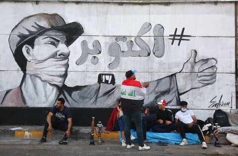 معترضان جوان زیر یک نقاشی دیواری در میدان تحریر که ماه اکتبر زمان شروع اعتراضات را به سادگی نشان می‌دهد