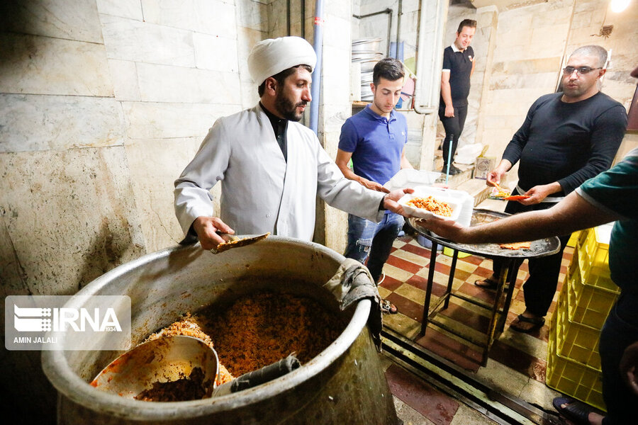 حجت‌الاسلام حسینی در حال آماده‌سازی غذای نذری جهت توزیع در میان عزاداران.