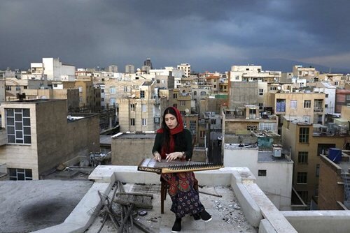 "مژگان حسینی" 28 ساله در حال نواختن ساز"قانون" در پشت بام خانه در تهران