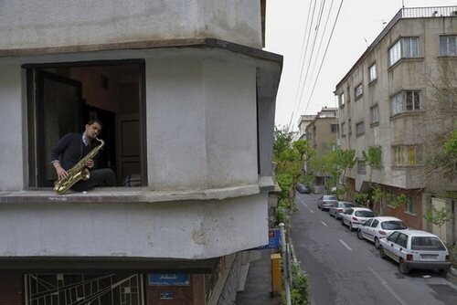 "محمد مالکی" 23 ساله عضو ارکستر ملی ایران در حال نواختن "ساکسیفون" در پنجره خانه در تهران 