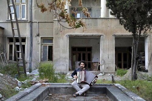 " کاوه غفاری" 26 ساله در حال نواختن آکاردئون در حیاط خانه در تهران 