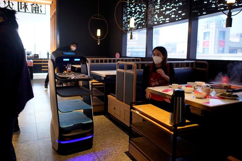 رباتی که در دوران شیوع کرونا در رستوران‌های چین به مشتریان سرویس‌دهی می‌کند.