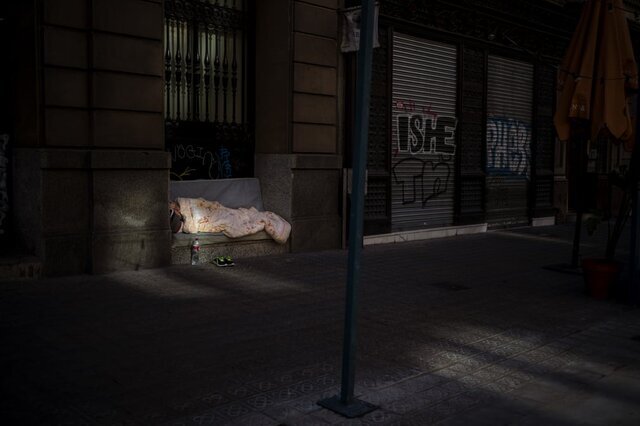  زنی در خیابان خالی خوابیده است که فروشگاه‌های آن به دلیل محدودیت‌های کرونا تعطیل هستند / بارسلونا / اسوشیتدپرس