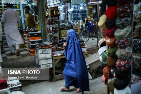 یک زن افغانستانی اهل شهر جلال‌آباد در حال گذر و خرید در بازار است.