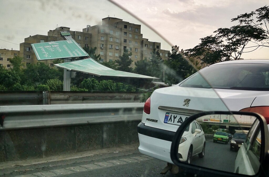 تصاویر بلایی که باد شدید تهران سر تابلوها و خودروها آورد | سقوط تابلوی مسیرنما روی خودروهای عبوری | ۲ نفر مجروح و به بیمارستان منتقل شدند
