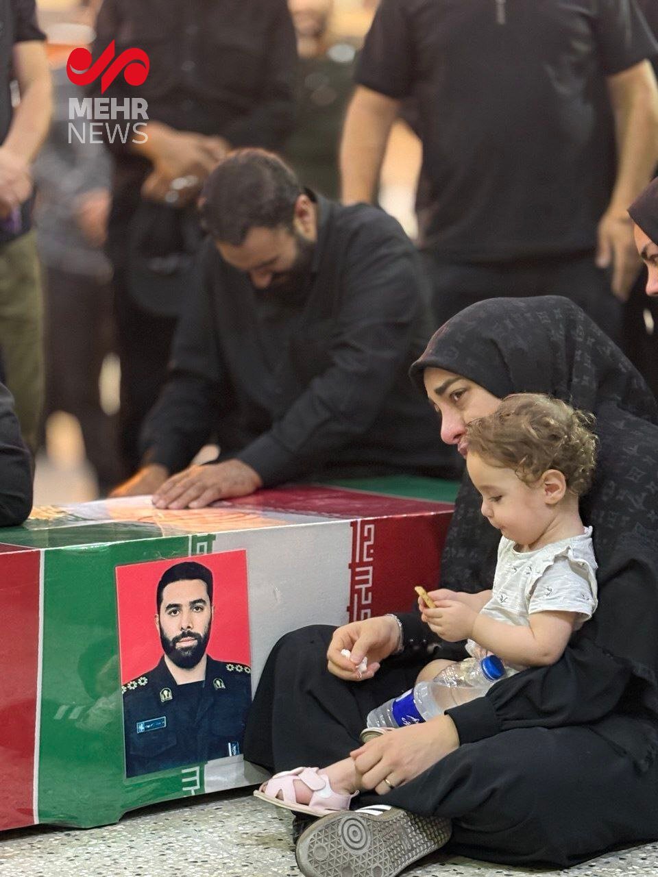 این عکس ایران را به گریه انداخت ؛ همسر و فرزند شهید رامین نصیری در کنار پیکر شهید