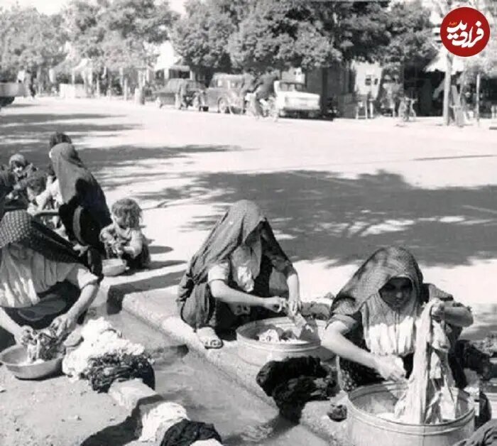زنان تهرانی در حال شستن لباس‌ در جوی آب کنار خیابان در دهه ۵۰ | عکس